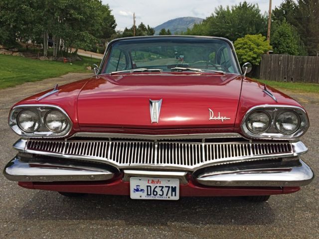 an old red car parked in a parking lot