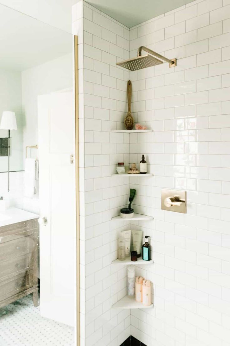 a white tiled bathroom with shelves on the wall