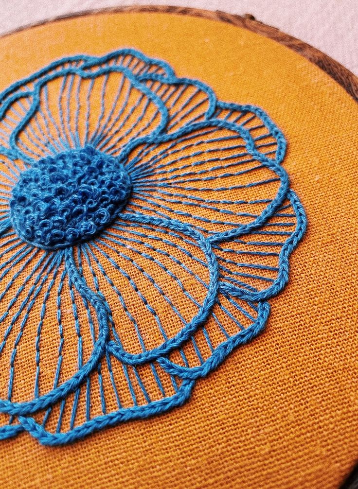 a close up of a piece of cloth with blue thread on it and an embroidered flower