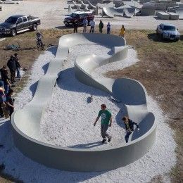 several people are standing in the sand next to a large sculpture that looks like a snake