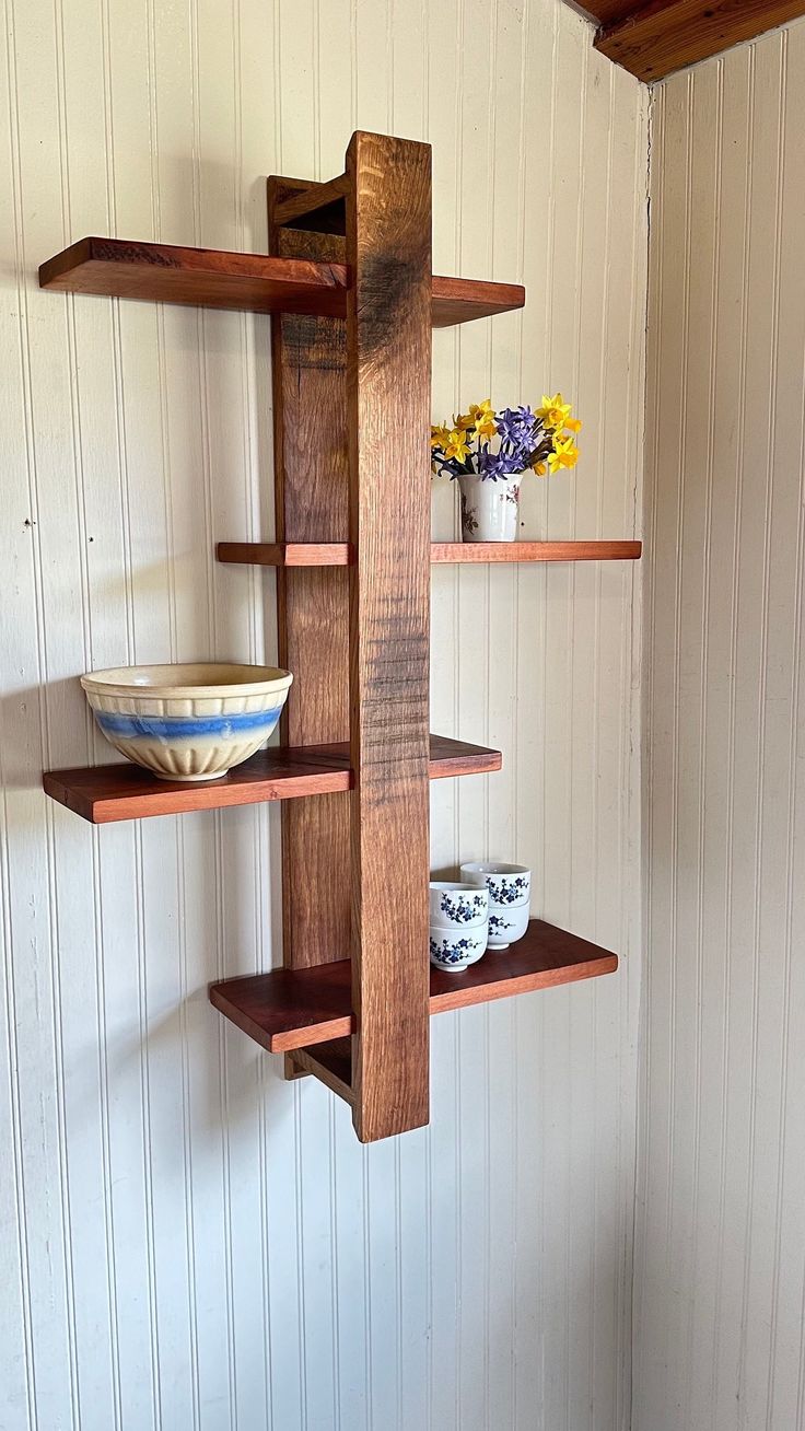 three wooden shelves with bowls and cups on them