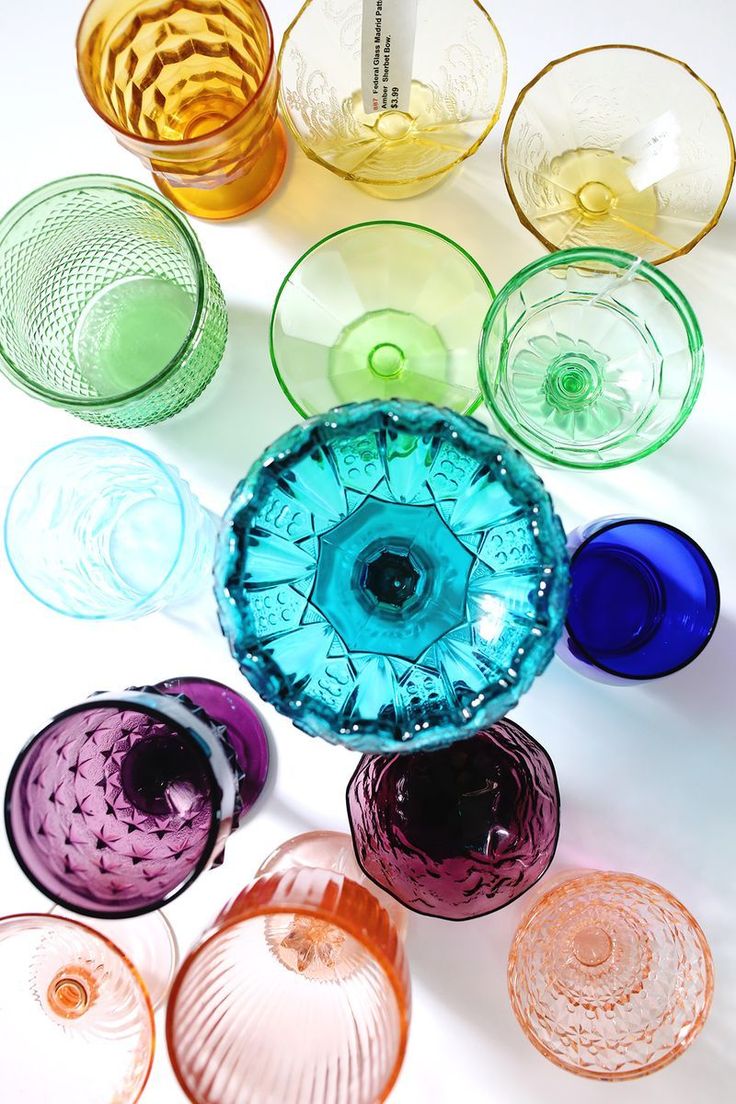 many different colored glass bowls on a white surface