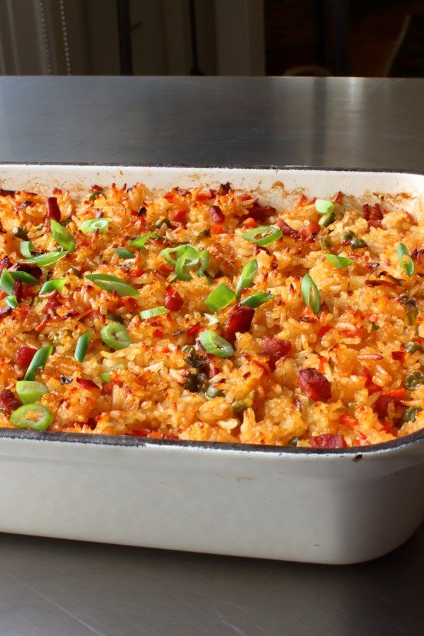 a casserole dish with rice and vegetables in it on a metal table top