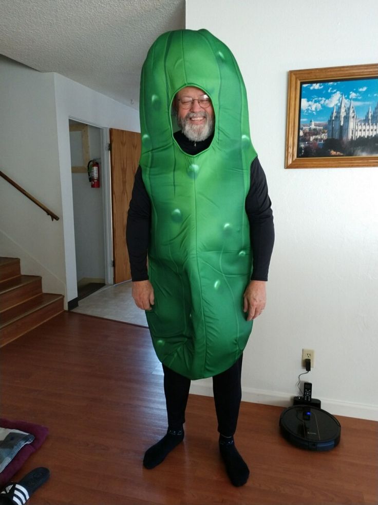 a man in a green pea costume standing on a hard wood floor