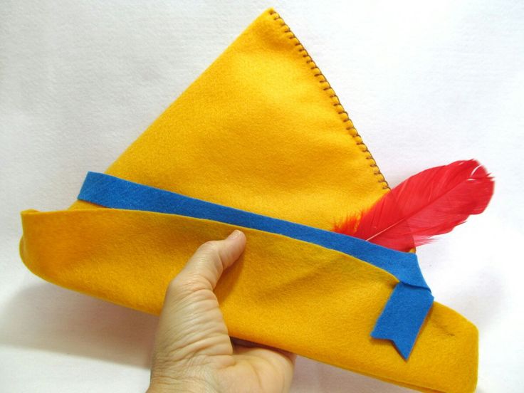 a hand is holding an origami hat with a red feather on the side