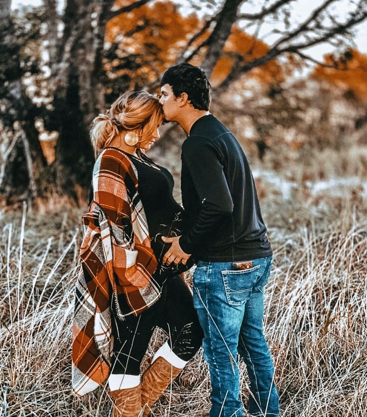 a man and woman are standing in the tall grass