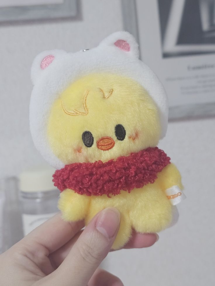 a yellow stuffed animal with a red scarf around it's neck is held up