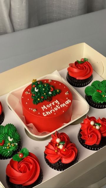 twelve cupcakes in a box decorated with red, green and white frosting