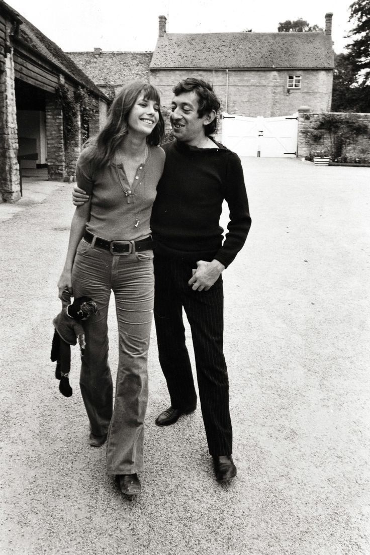 a man and woman standing next to each other in front of an old brick building