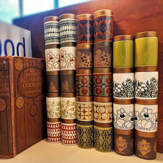 a stack of books sitting on top of a table next to a book case filled with different types of coffee cups