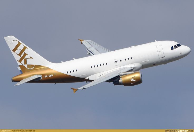 a large white and gold airplane flying in the sky with it's landing gear down