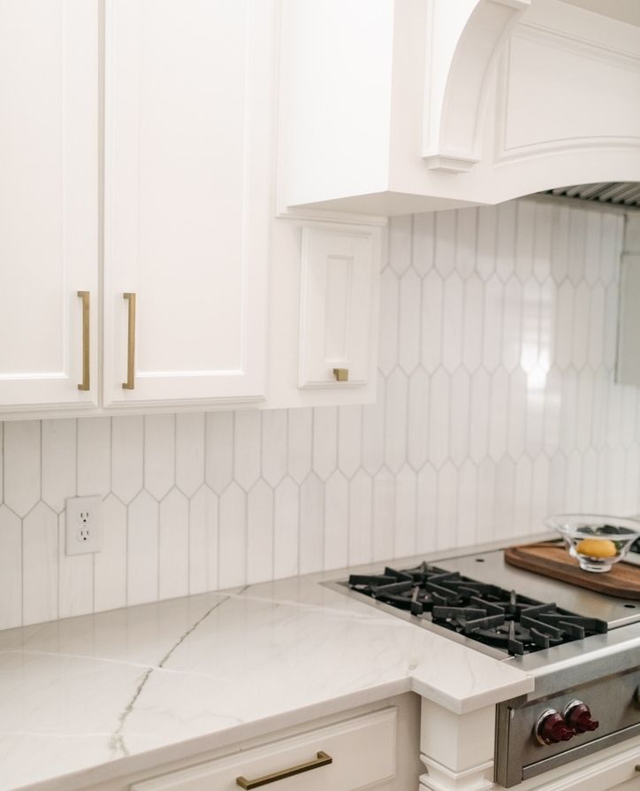 a kitchen with white cabinets and marble counter tops is pictured in this image, there are two burners on the stove