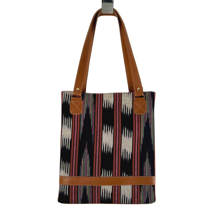 Looking for a uniquely gorgeous structured bag? Look no further! The jaspe (ikat) structured tote is made of handspun and handwoven fabric designed by the women of Ruk’U’X Keem of San Juan La Laguna, Guatemala. Cuero Malec, a Guatemalan leather shop, transforms the fabric into gorgeous, durable bags. Square Woven Bags For Everyday Use, Square Woven Bag For Everyday Use, Artisan Fair Trade Shoulder Bag For Daily Use, Artisan Shoulder Bag For Daily Use, Fair Trade, Handwoven Square Shoulder Bag For Everyday Use, Natural Shoulder Bag With Weaving Work For Daily Use, Everyday Shoulder Bag With Weaving Work, Travel Tote Shoulder Bag With Weaving Work, Everyday Weaving Work Shoulder Bag