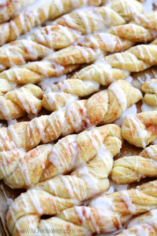 cinnamon rolls with icing sitting on top of a baking sheet covered in glaze