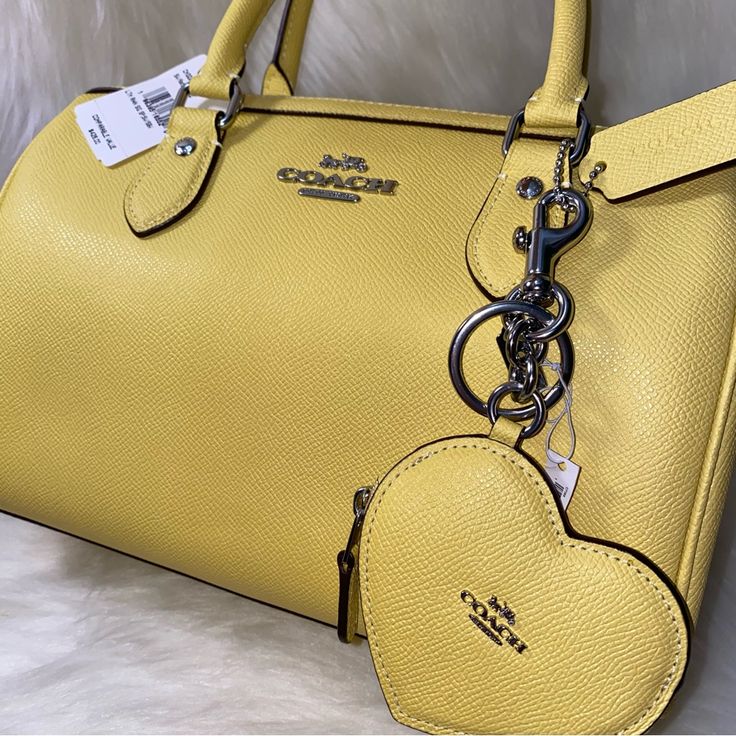 1. Coach Rowan Satchel Bag With Signature Canvas Strap New 100 % Authentic Retro Yellow With Silver Tone Hardware Approximate Measurements L 10.0" H 6.5" W 5.5" Crossgrain Leather Signature Coated Canvas Fabric Lining Handles With 4.25" Drop Long Strap With 23" Drop Included 2. Coach Heart Bag Charm Nwt 100 % Authentic Retro Yellow Silver Hardware Crossgrain Leather Zip Closure Fabric Lining Attached Split Key Ring Dogleash Clip Approximate Measurements 3 1/2" L X 3" H X 5" W Smoke And Pets Free Yellow Top Handle Satchel For Travel, Yellow Satchel With Detachable Strap For Shopping, Yellow Top Handle Satchel With Detachable Strap, Yellow Top Handle Satchel For Everyday Use, Yellow Handheld Satchel For Travel, Yellow Satchel With Detachable Strap, Yellow Satchel With Detachable Strap And Double Handle, Classic Yellow Bag With Removable Pouch, Classic Yellow Bags With Removable Pouch