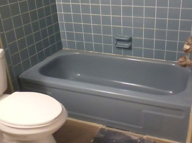 a bathtub and toilet in a bathroom with blue tiles