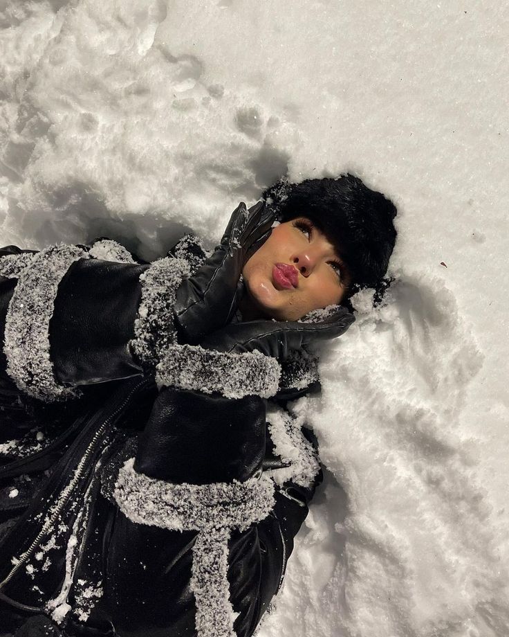 a doll is laying in the snow wearing black gloves