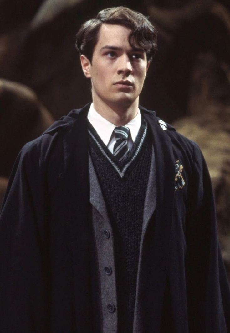 the young man is dressed in a harry potter costume and wearing a black robe with a white collar