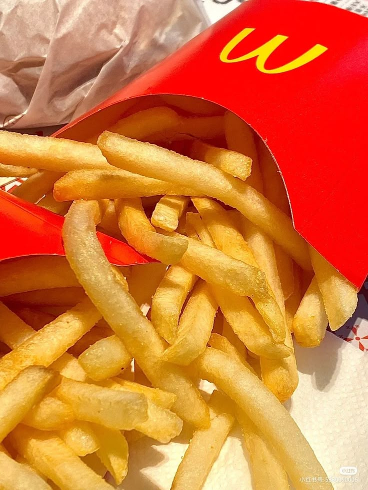 french fries with ketchup and mustard in a red container on top of a table