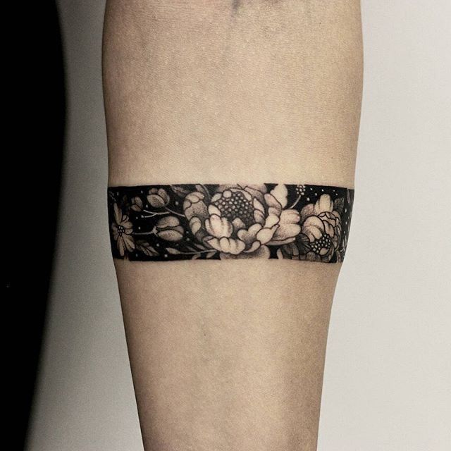 a black and white photo of a woman's lower leg with flowers on it