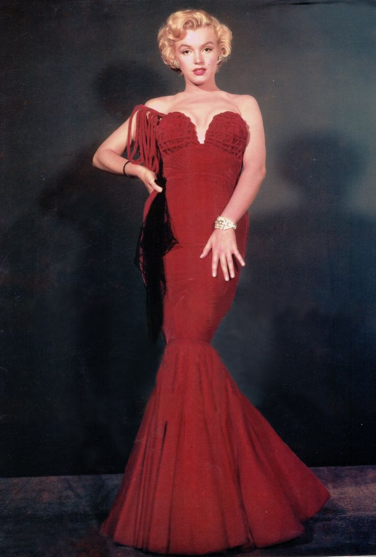 a woman in a red dress is posing for a photo with her hands on her hips