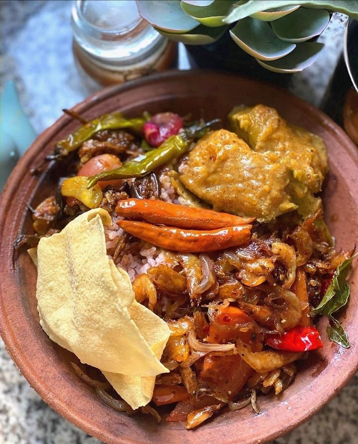 a bowl filled with different types of food on top of a table next to a potted plant