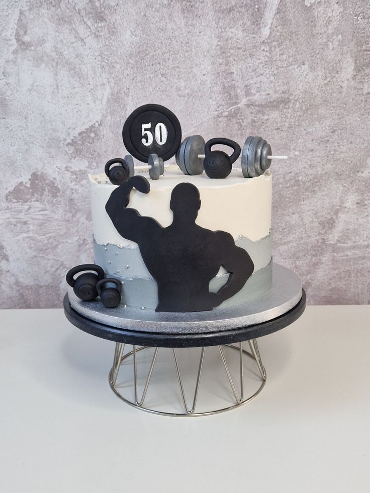 a cake decorated with an image of a bodybuilding man and dumbbells on top