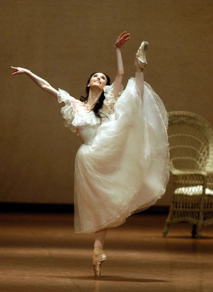 a ballerina in white is posing for the camera with her arms outstretched and legs spread out