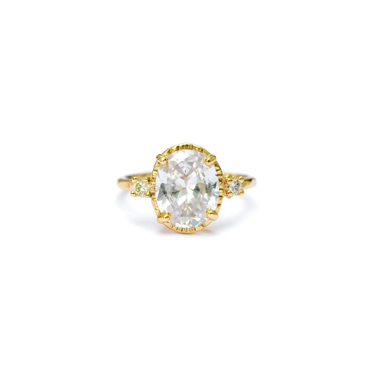 a yellow gold ring with an oval cut diamond in the center and three small diamonds on each side