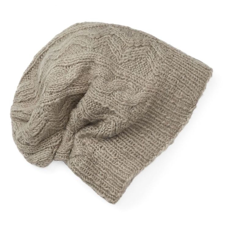 a knitted beanie is shown on a white background, with the top knot pulled up