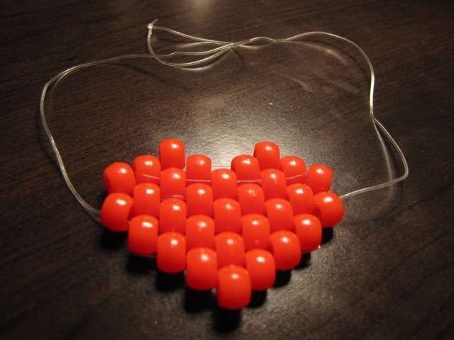 an orange beaded heart on a wooden table