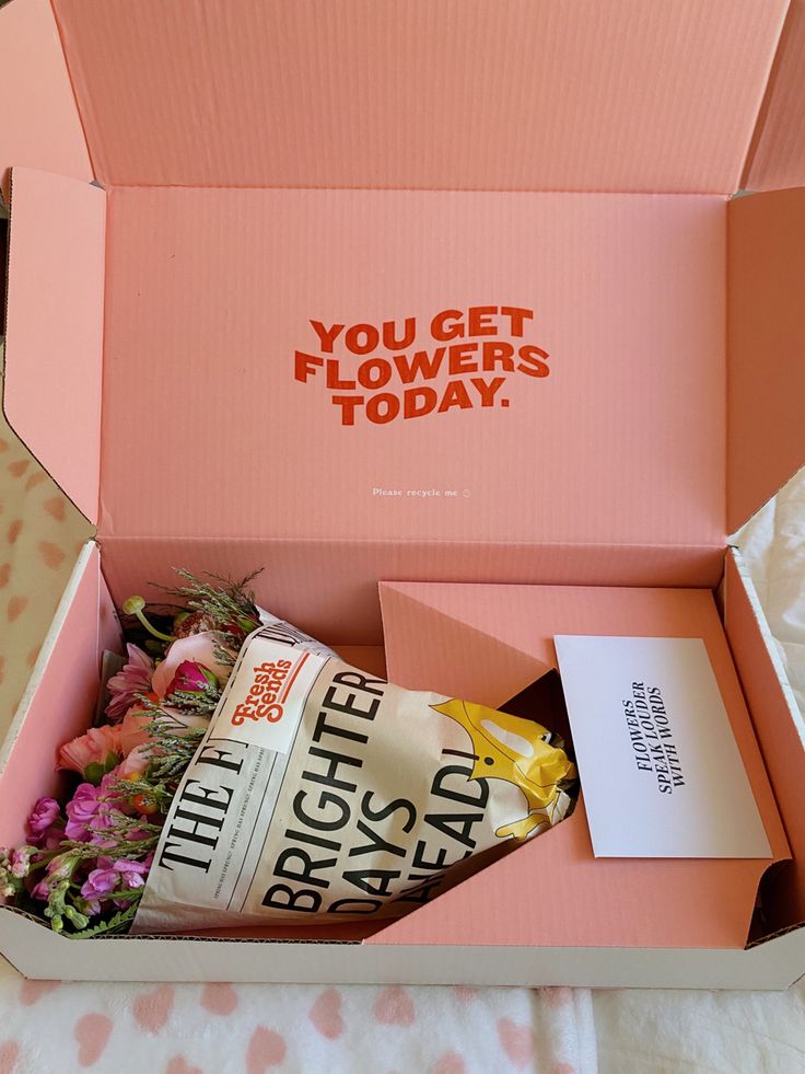 an open pink box with flowers in it