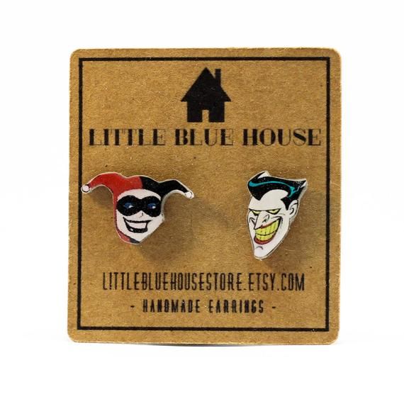 two little blue house enamel pin badges in front of a cardboard box with the words little blue house on it