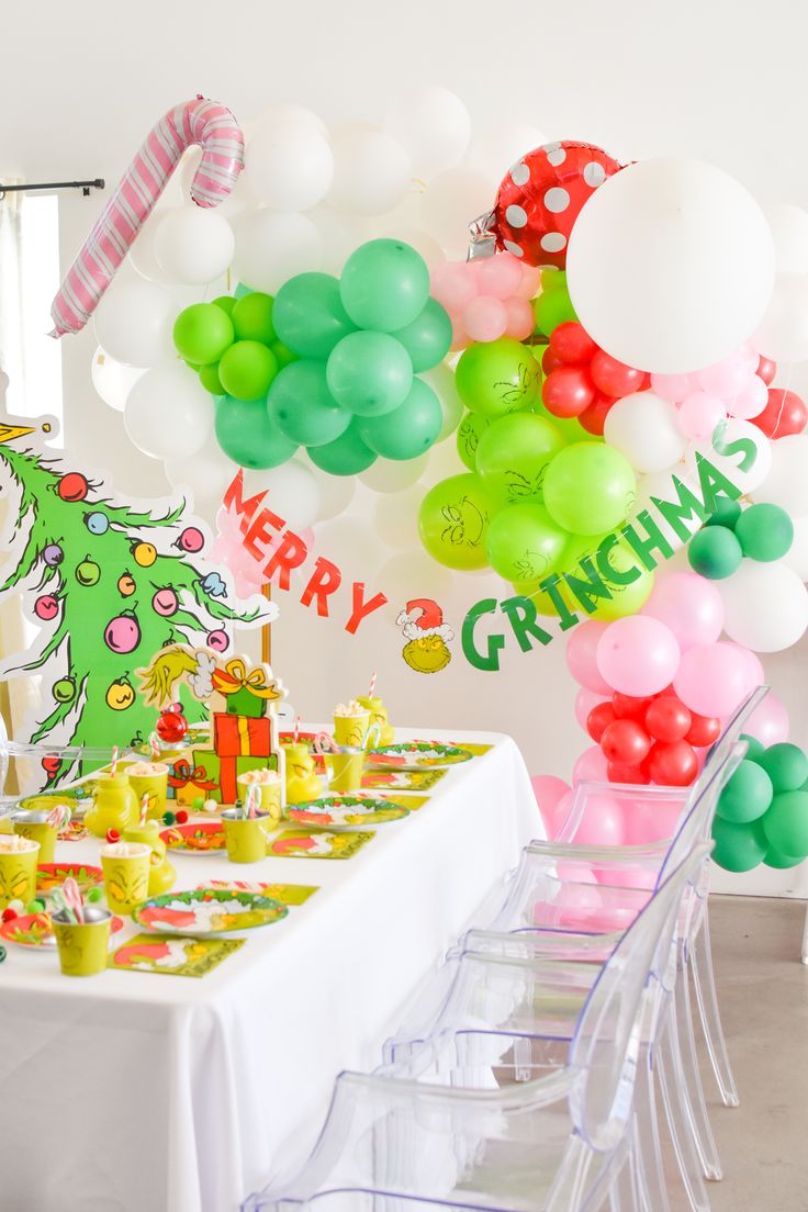 a table set up for a christmas party with balloons and decorations on the wall behind it