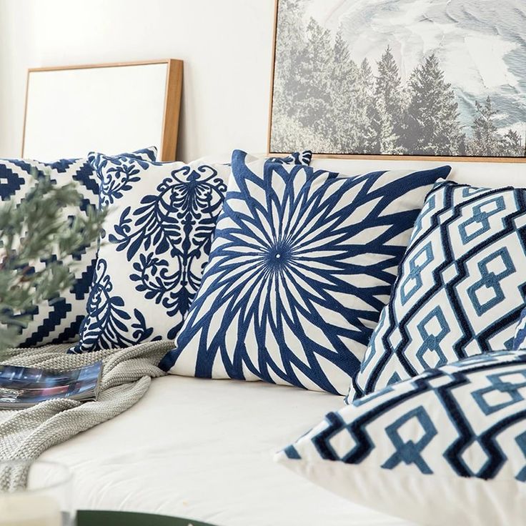 blue and white pillows sitting on top of a couch next to pictures hanging on the wall