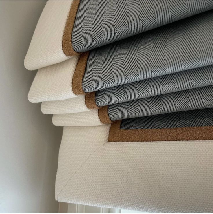 four different shades of gray and white fabric on a window sill with brown trim