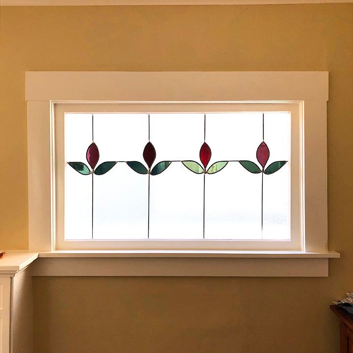 a bathroom window with three flowers on it