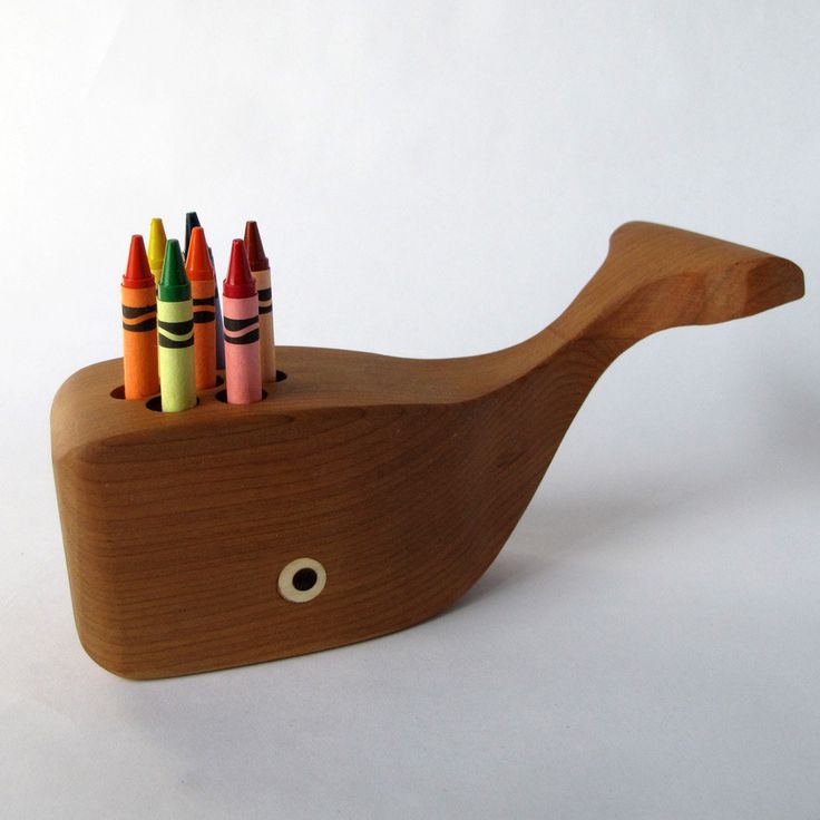 a wooden toy boat with crayons in it