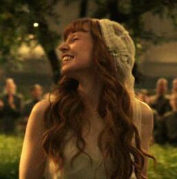 a woman with long red hair wearing a white dress and a knitted hat laughing