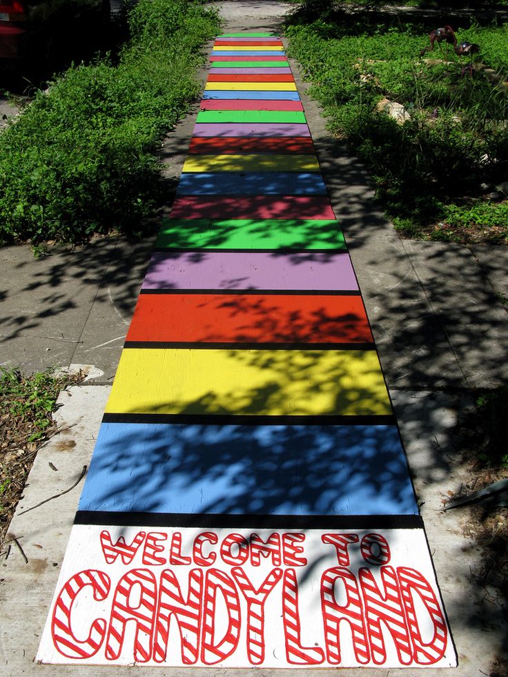 there is a rainbow painted path that says welcome to candy land