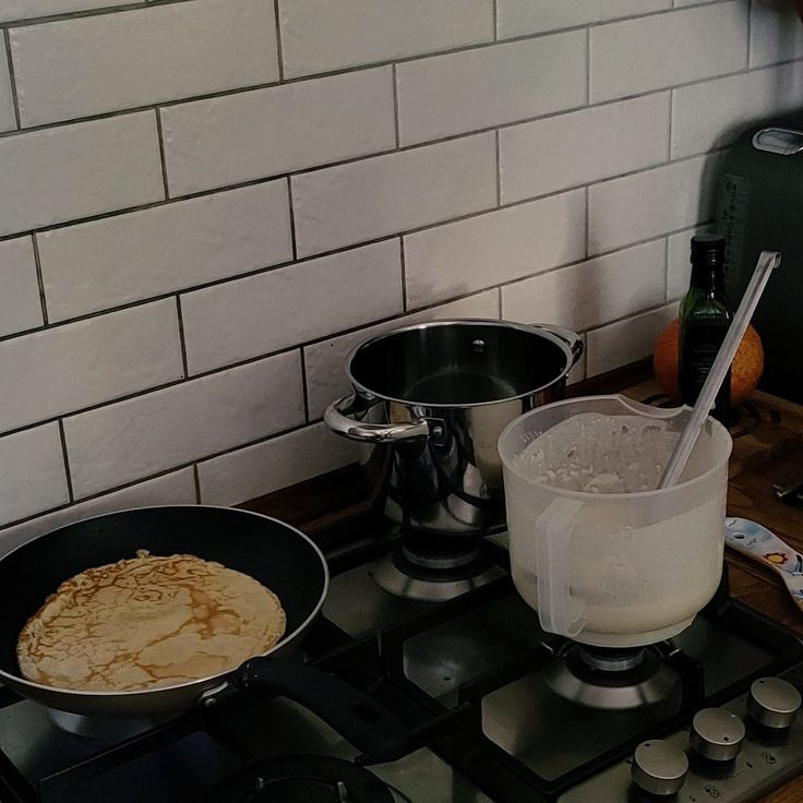 a stove top with two pans on it and some food in the bowl next to them