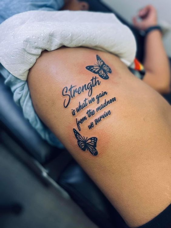 a woman with a butterfly tattoo on her arm and the words strength is what we gain,