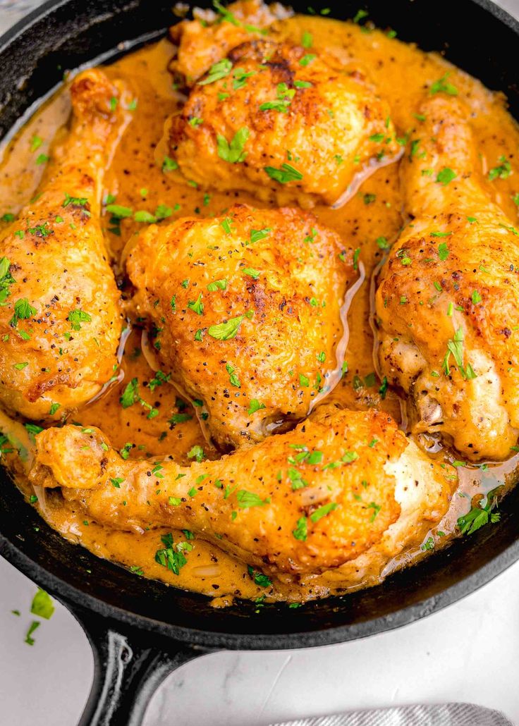 chicken thighs in a skillet with gravy and parsley