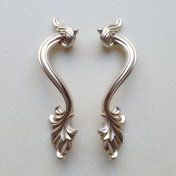 two silver colored metal handles on a white surface