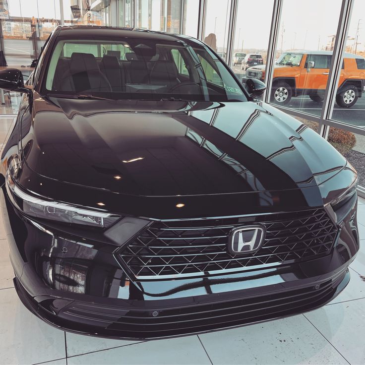 the front end of a black car in a showroom