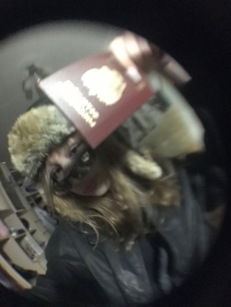 the reflection of a person in a mirror wearing a hat and jacket with fur on it