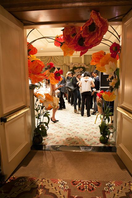 a group of people standing in an open doorway with paper flowers hanging from the ceiling