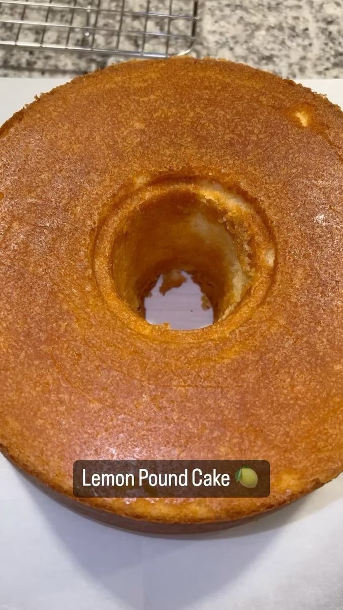 a lemon pound cake sitting on top of a white plate with a metal rack behind it