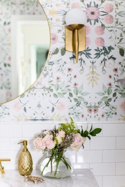 a bathroom with floral wallpaper and gold faucet on the sink countertop