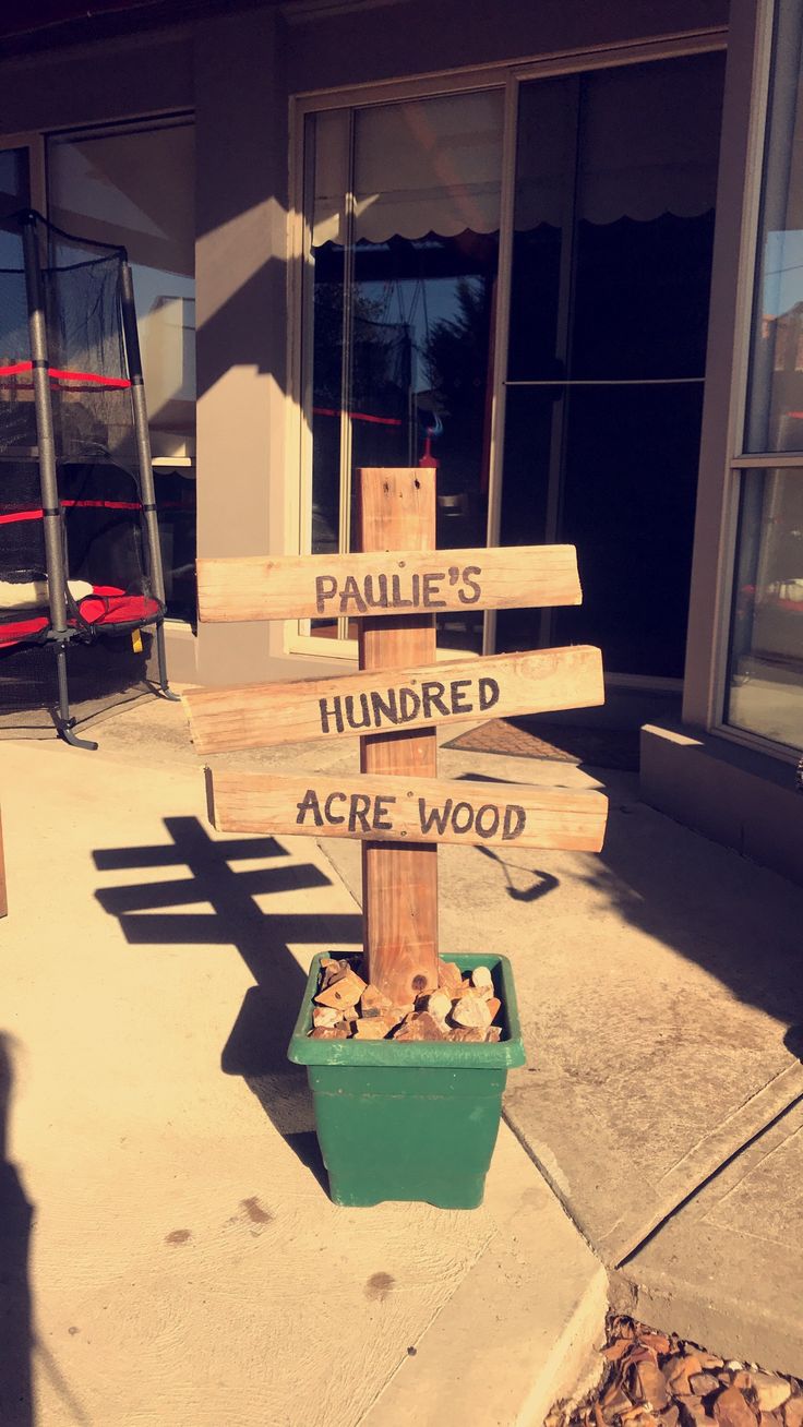 a wooden sign sitting on the side of a building next to a planter filled with rocks